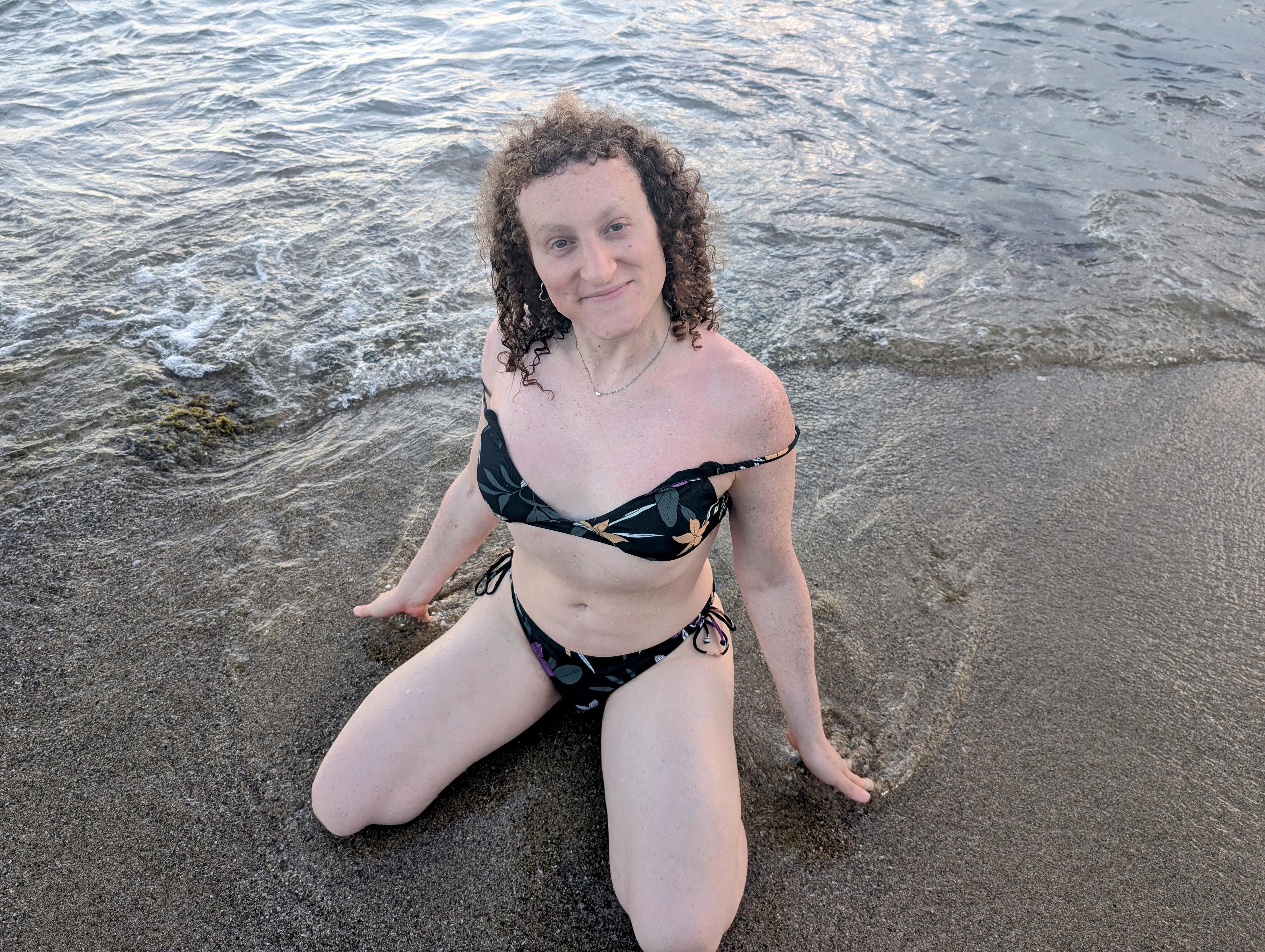 Face out: a picture of Violet kneeling on a beach looking up at the camera.