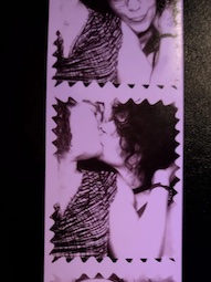 A film strip printed from a photo booth showing Violet and Velma kissing and snuggling together.